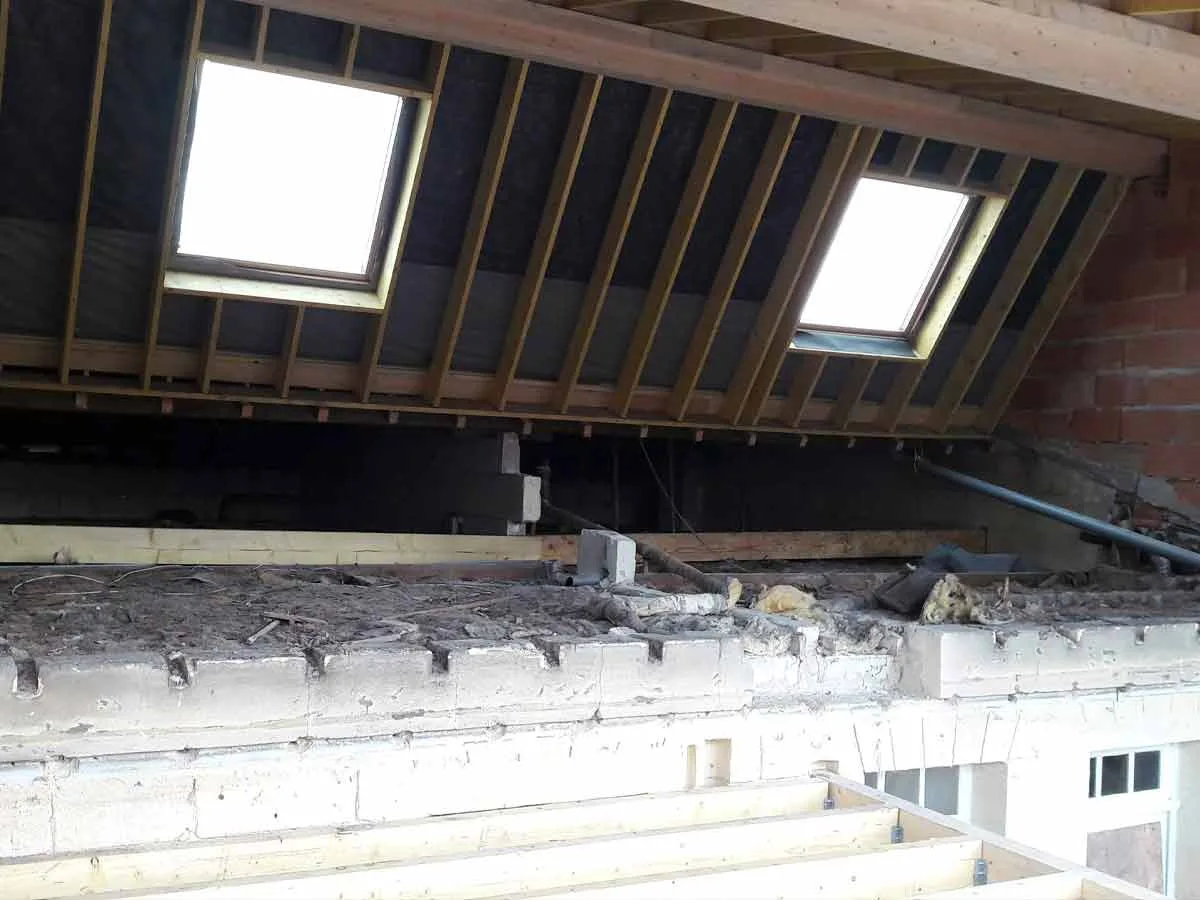 Deux fenêtres de toit installées entre les chevrons, vues depuis l'intérieur des combles