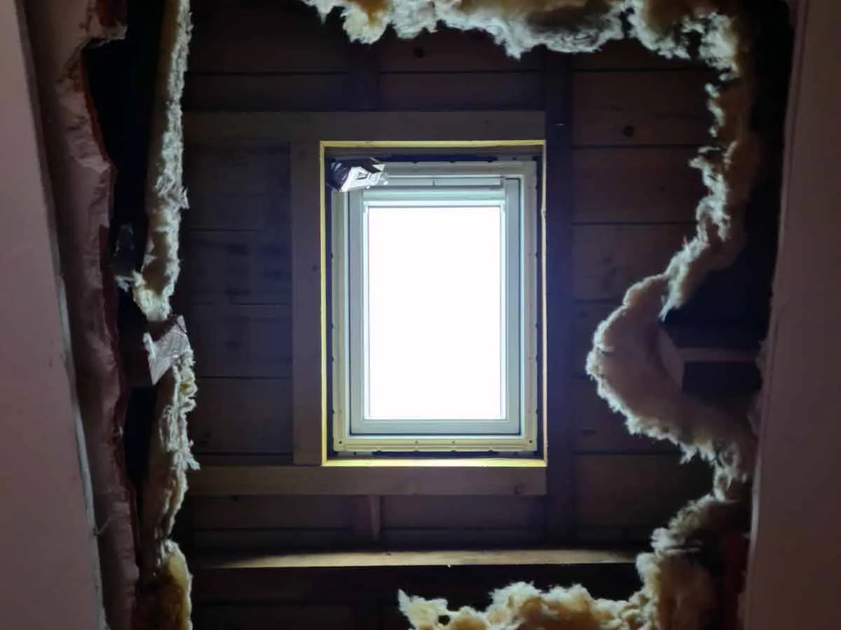 Fenêtre de toit vue de l'intérieur, entourée de l'isolation posée dans les rampants
